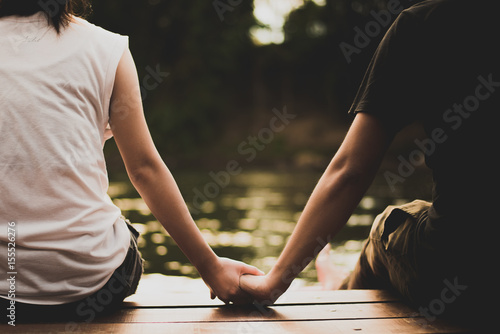 A romantic couple hold each other hand beside the lake in vintage tone.