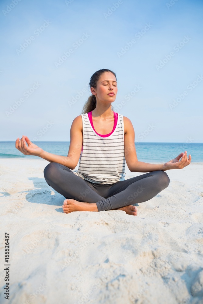 Full length of woman with eyes closed meditating at beach Full length of woman with eyes closed meditating at beach