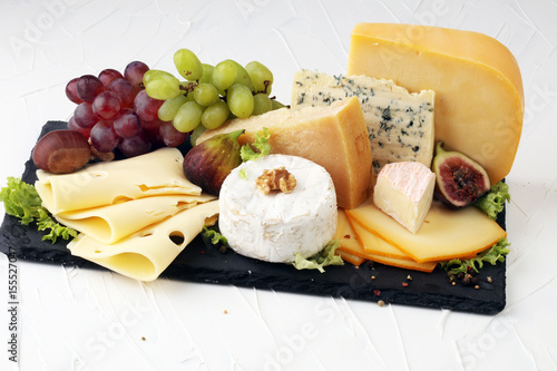 Cheese platter with different cheese, fig, salad and grapes