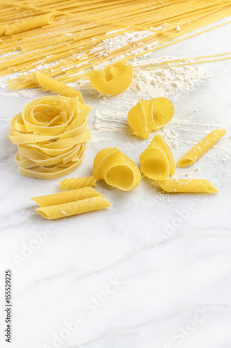 Various types of pasta on marble with copyspace