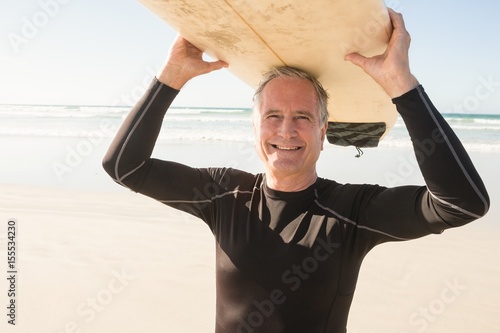 Photography Portrait of smiling senior man carrying surfboard