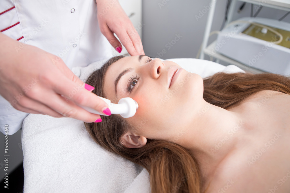 Woman getting laser face treatment in medical spa center