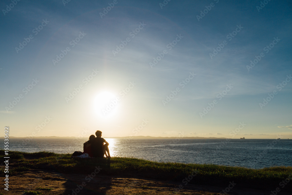 Silhouette of a couple embracing during sunset facing the sea