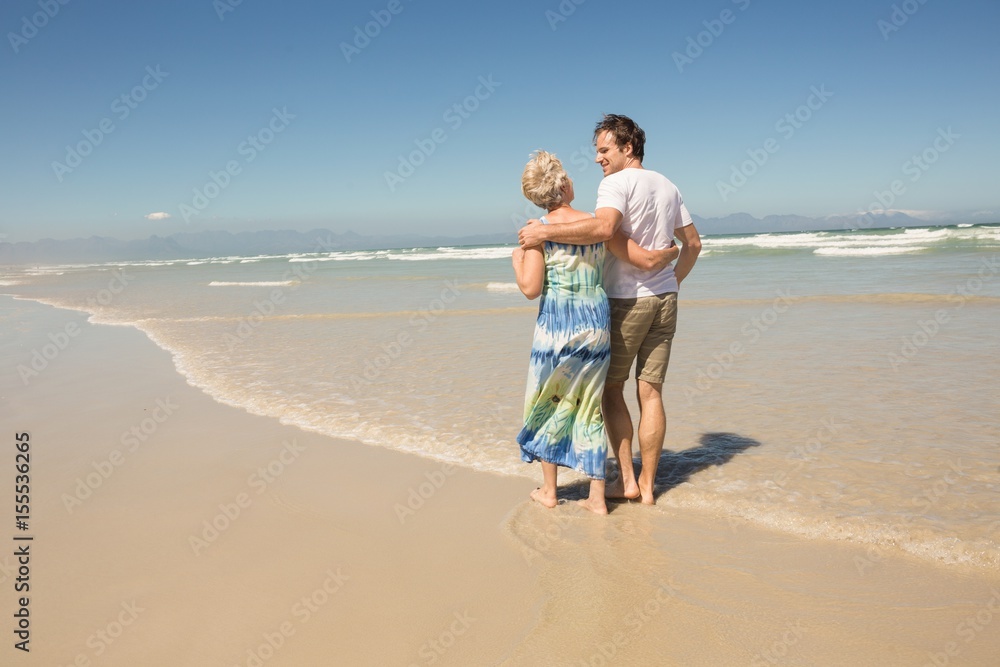 Rear view of happy man walking with mother on sand Rear view of happy man walking with mother on sand