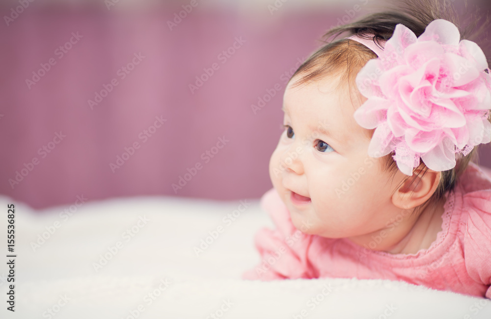 Cute little baby girl lying in the bed in pink dress. Three month old infant child on white soft blanket Cute little baby girl lying in the bed in pink dress. Three month old infant child on white soft blanket