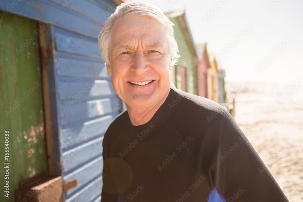 Fototapeta premium Portrait of senior man standing by beach huts