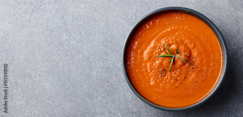 Tomato soup in a black bowl on grey stone background. Top view. Copy space photo