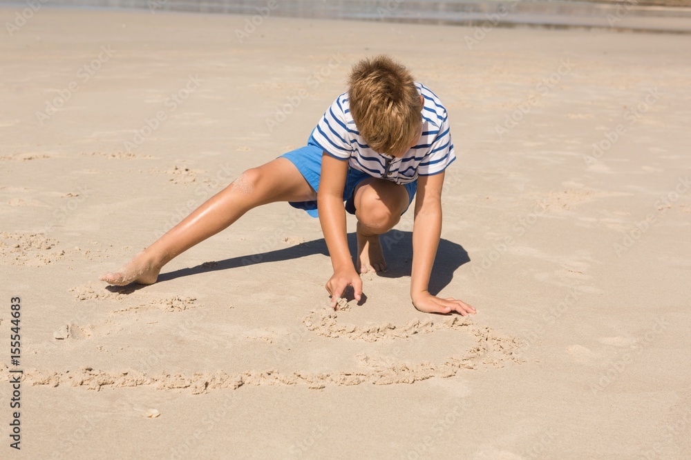 Boy playing with sand while crouching at beach Boy playing with sand while crouching at beach