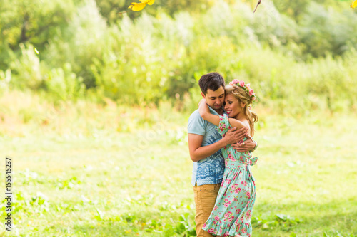 Couple embracing on the countryside. Young romantic man and woman standing and hugging each other with tenderness on nature. Young love concept.