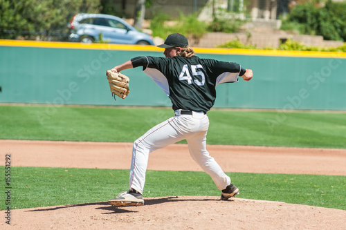 Mens' baseball pitcher winding up to throw the curveball. 