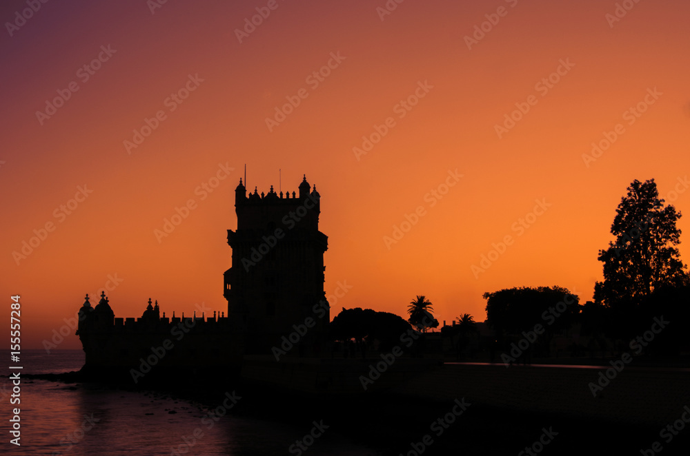 Sylwetka wieży Belem w Lizbonie. Pomarańczowe niebo zachodzące słońce. 