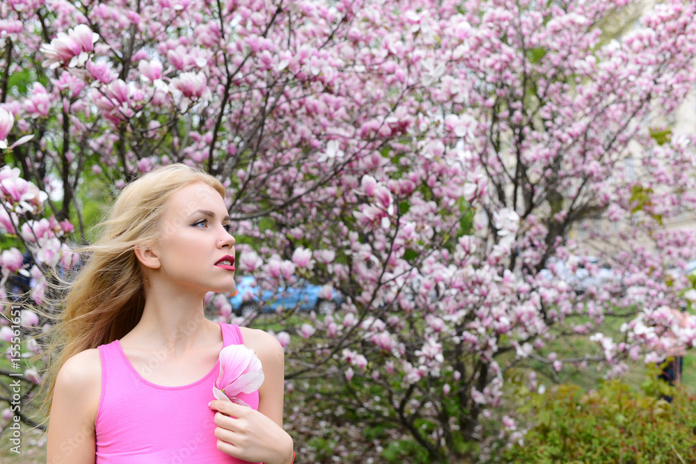 pretty girl hold magnolia flower at blossoming tree, spring garden pretty girl hold magnolia flower at blossoming tree, spring garden