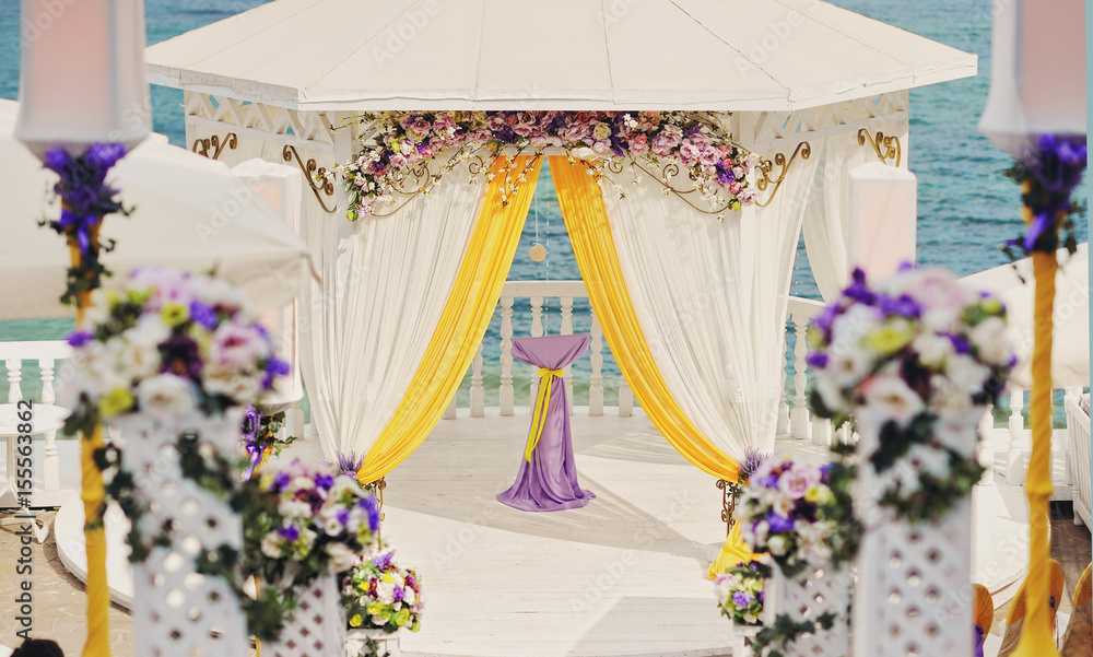 white wedding arch with flowers and yellow elements of a decor