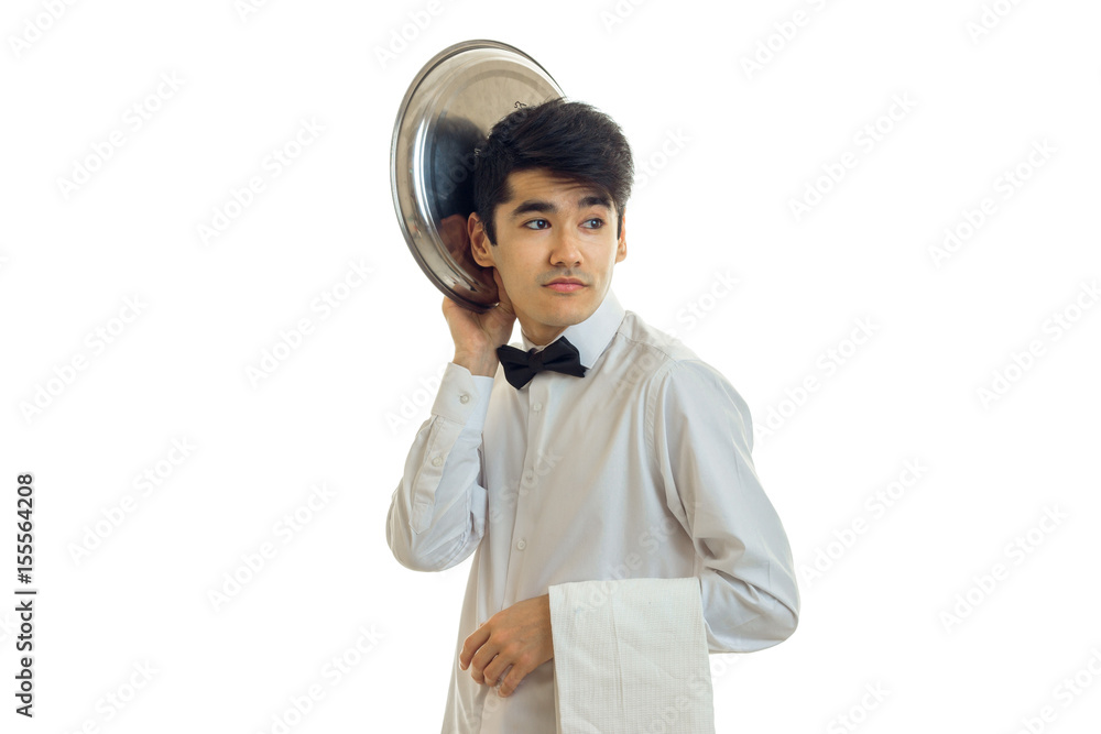funny handsome waiter looks away and keeps the dish tray near his head isolated on white background funny handsome waiter looks away and keeps the dish tray near his head isolated on white background
