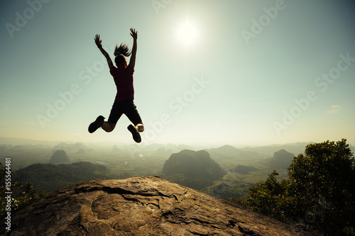 freedom woman hiker jumping on sunrise mountain top