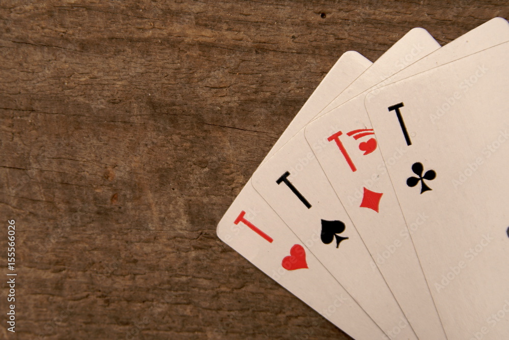 Four playing card aces on a wooden table.