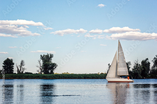 Yachts at sailing regatta. Beautiful ship yachts with white sails in the Dnieper river on a background of the blue sky with clouds. Sailing yacht race. Yachting outdoor lifestyle. photo