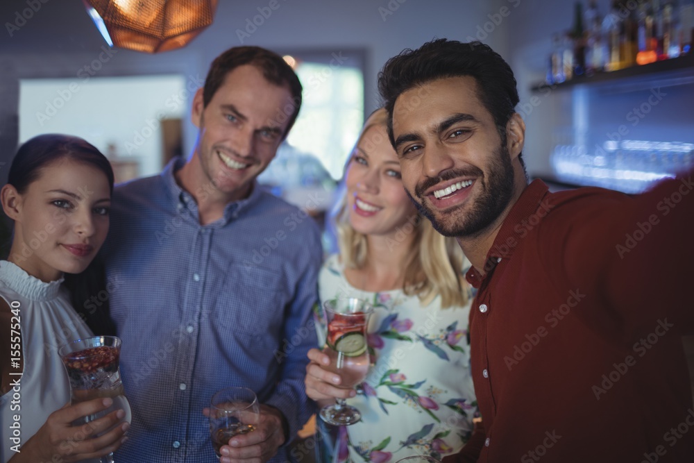 Smiling two couples holding glasses of cocktail