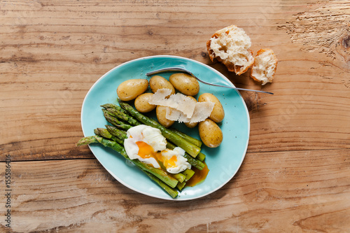 Light spring lunch on the plate. Fried asparagus, fresh potatoes and poached egg with parmesan cheese. healthy food.