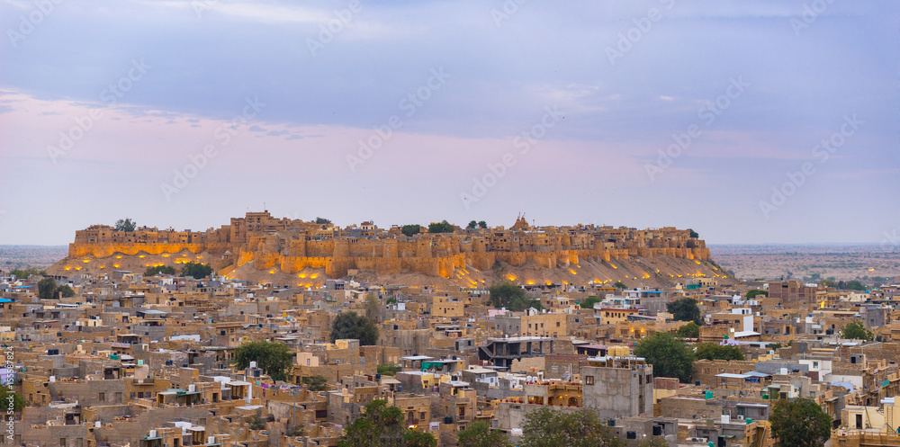 Obraz premium Jaisalmer pejzaż miejski przy zmierzchem. Majestatyczny fort dominujący nad miastem. Sceniczny podróży miejsce przeznaczenia i sławna atrakcja turystyczna w Thar pustyni, Rajasthan, India.