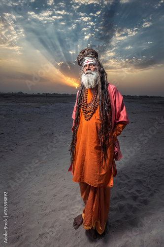 Portrait of sadhu standing with sunrise behind him, Varanasi, India. photo