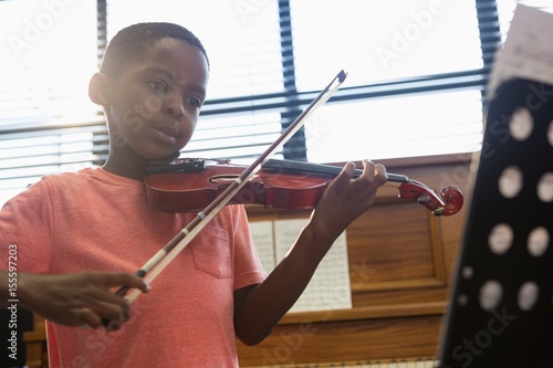 Fototapeta Chłopiec grający na skrzypcach siedząc w klasie