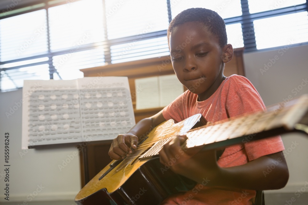 Naklejka premium Boy playing guitar in class