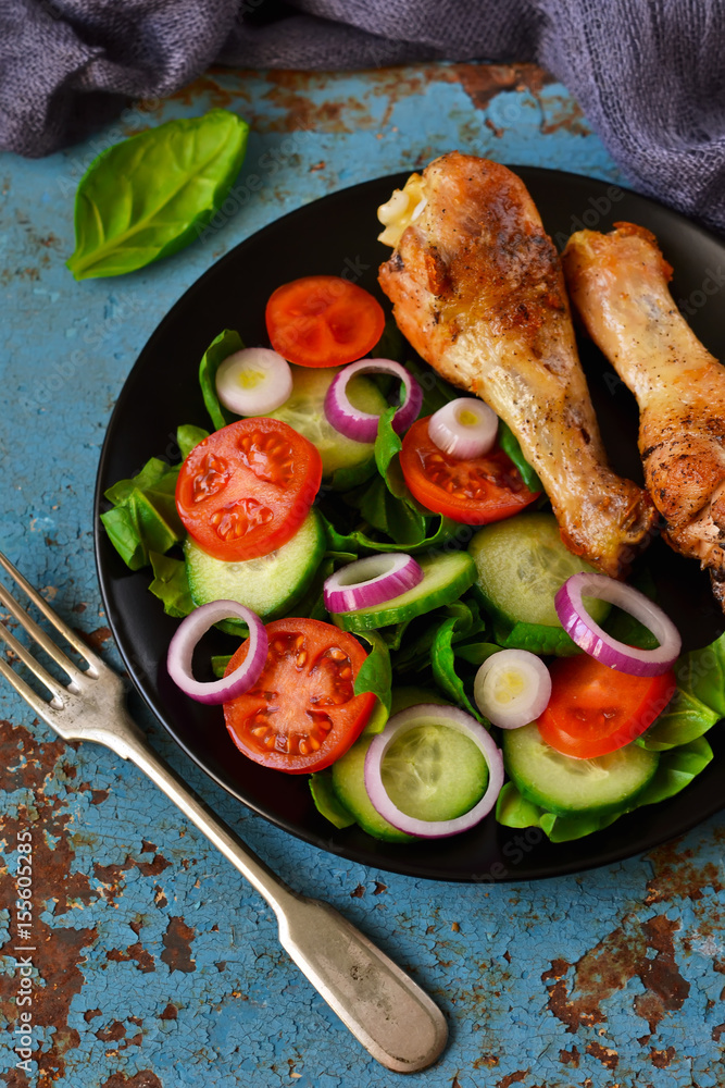 Baked chicken with a side dish of vegetable salad on the old, blue background Baked chicken with a side dish of vegetable salad on the old, blue background