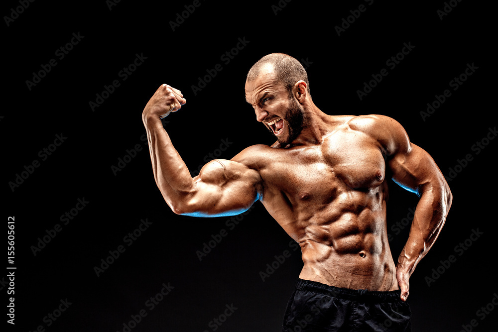 Strong bodybuilder man with perfect abs, shoulders,biceps, triceps and  chest showing his biceps. Scream motivation. Stock Photo