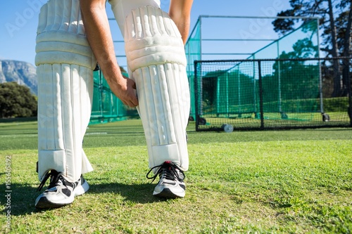 Low section of cricket player tying kneepads