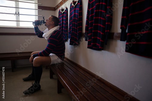 Photos Tired player drinking water while sitting on bench