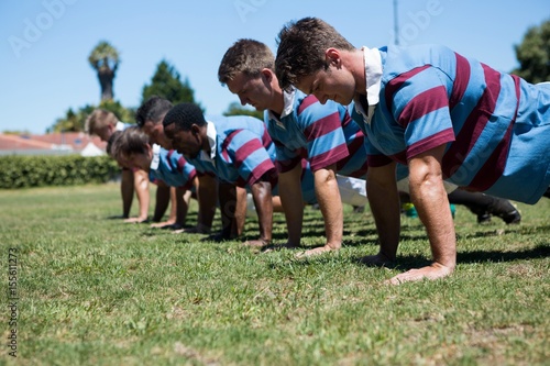 Close up of players doing push up at grassy field