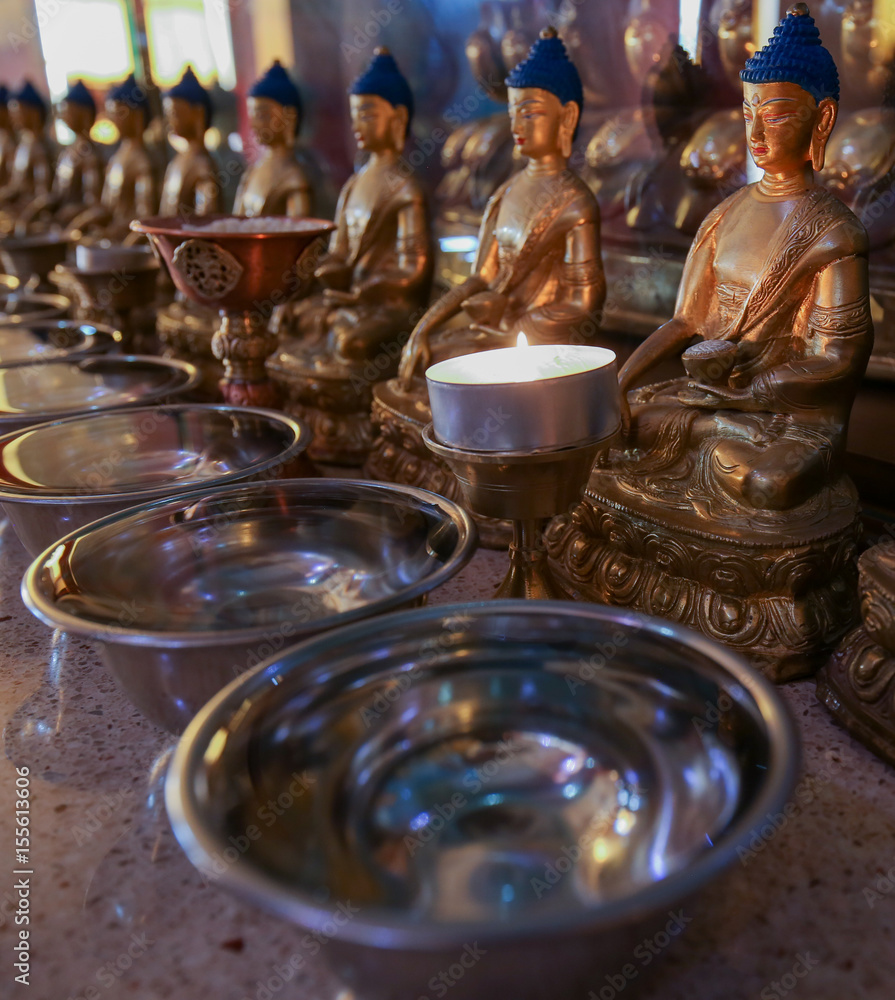 Figures of the sitting Buddha in front of the candle in the temple