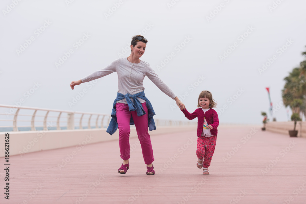 Obraz premium mother and cute little girl on the promenade by the sea