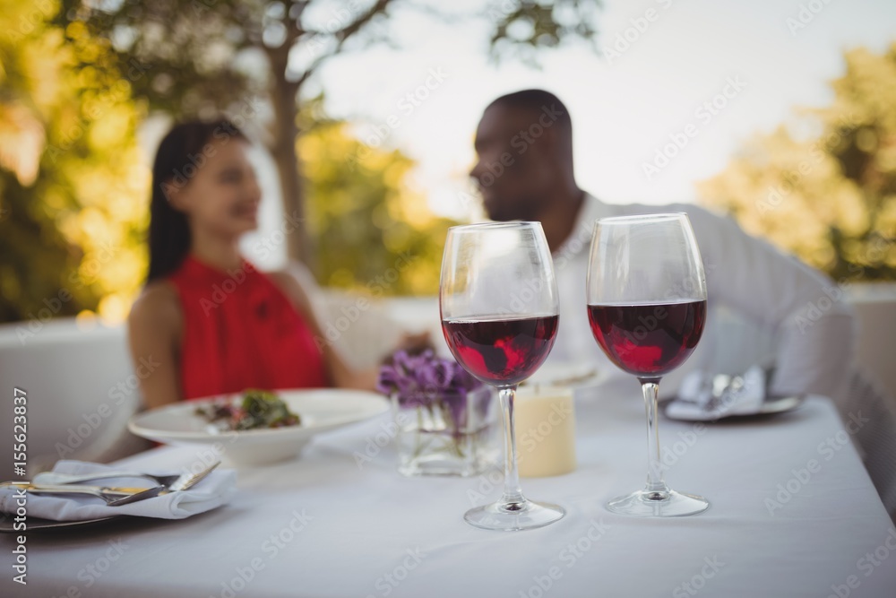 Two glasses of red wine with couple in background