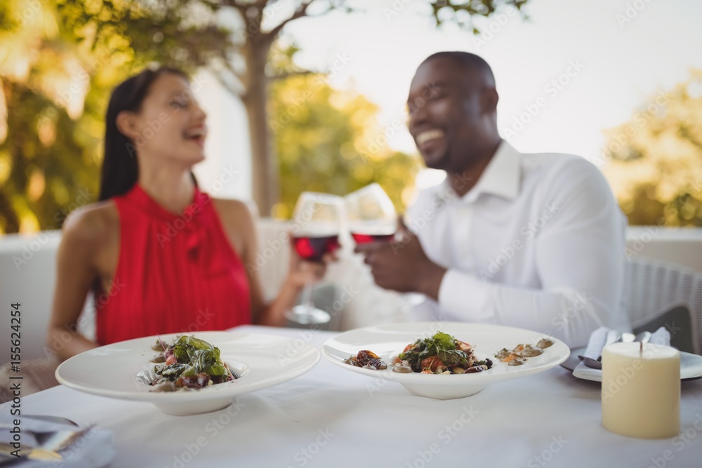Meal served while couple toasting their wine glasses