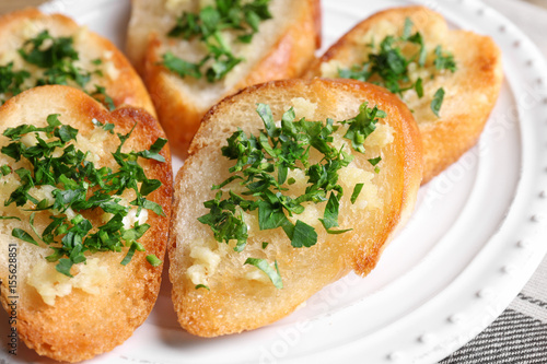 Tasty bread slices with garlic and herbs on plate