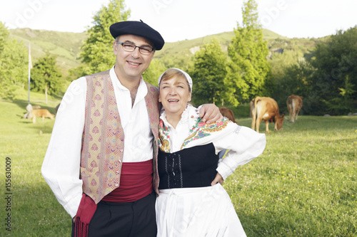 Couple dressed with one of the traditional Basque Country dresses, outdoors, smiling on the meadow.
