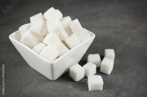 Bowl with sugar cubes on grey table