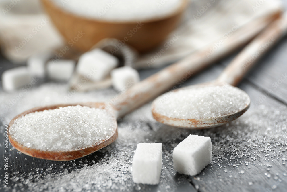 Wooden spoons with sugar on table, closeup Wooden spoons with sugar on table, closeup