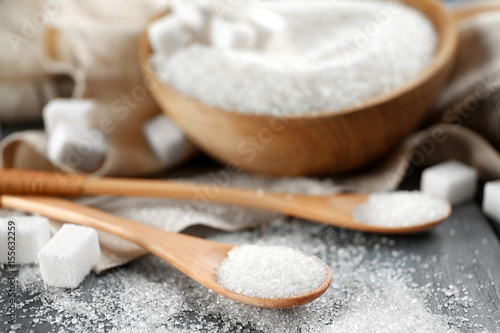 Bowl and spoons with sugar on wooden table, closeup