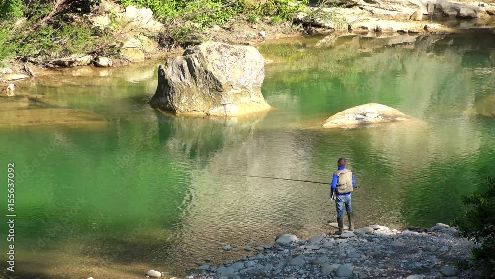 fisherman launching line and pasture while fishing on bank of green river fisherman launching line and pasture while fishing on bank of green river