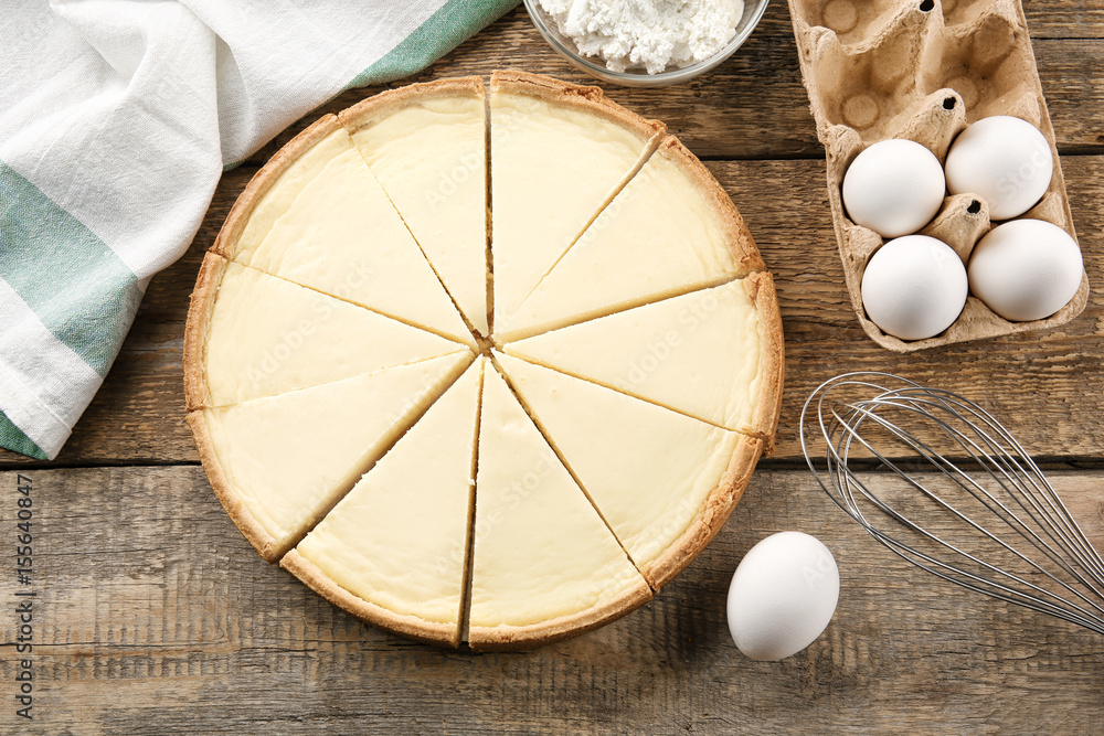 Composition with tasty homemade cheesecake and ingredients on wooden table Composition with tasty homemade cheesecake and ingredients on wooden table