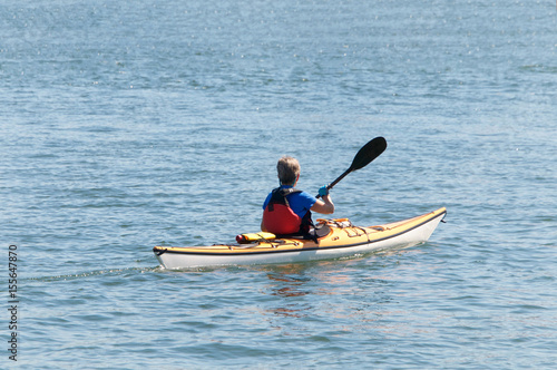 Lone kayak with older female paddling in open water away from viewer © sheilaf2002