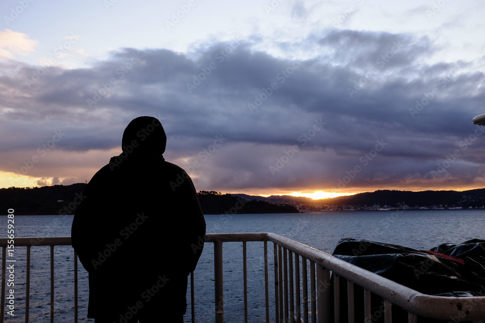 A man watches sunset from a ferry