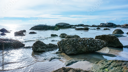 Tropical stone beach with clear water and blue sky