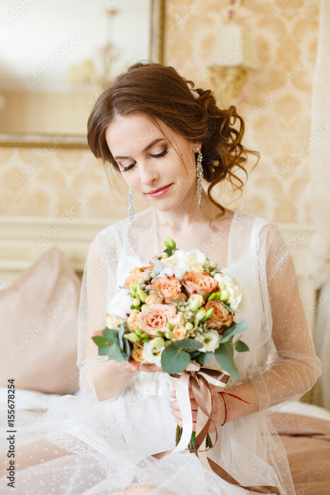 Pretty young Bride. Boudoir morning of the bride. Looking on her bouquet