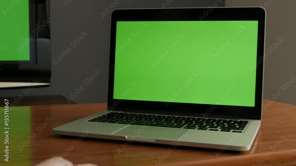 Laptop computer with green screen, corner of television in background. Livingroom Laptop computer with green screen, corner of television in background. Livingroom