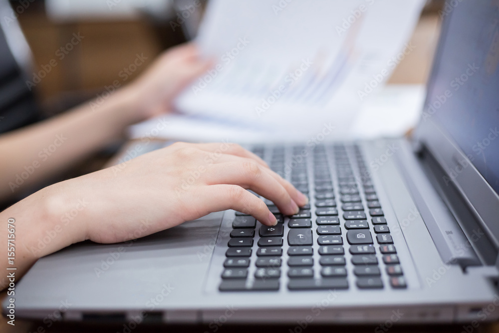 close up hand of businesswomen typing on laptop keyboard and hold document at workplace. business people and technology concept. close up hand of businesswomen typing on laptop keyboard and hold document at workplace. business people and technology concept.