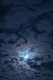 Full moon in the clouds in the night sky.